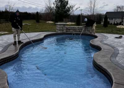 Two pool contractors cleaning a newly constructed inground pool
