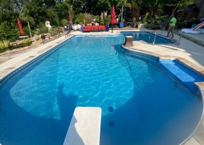 Professional pool cleaning service by Accurate Pool and Landscape in St. Louis, showing a technician skimming debris from the pool surface for routine maintenance.